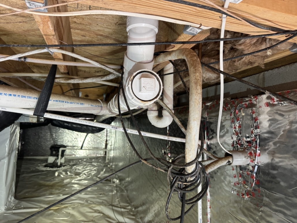 Encapsulated crawl space with a drain pipe cleanout in Carolina Trace Country Club, Sanford, NC, inspected by Realm Inspections for moisture control and plumbing access.